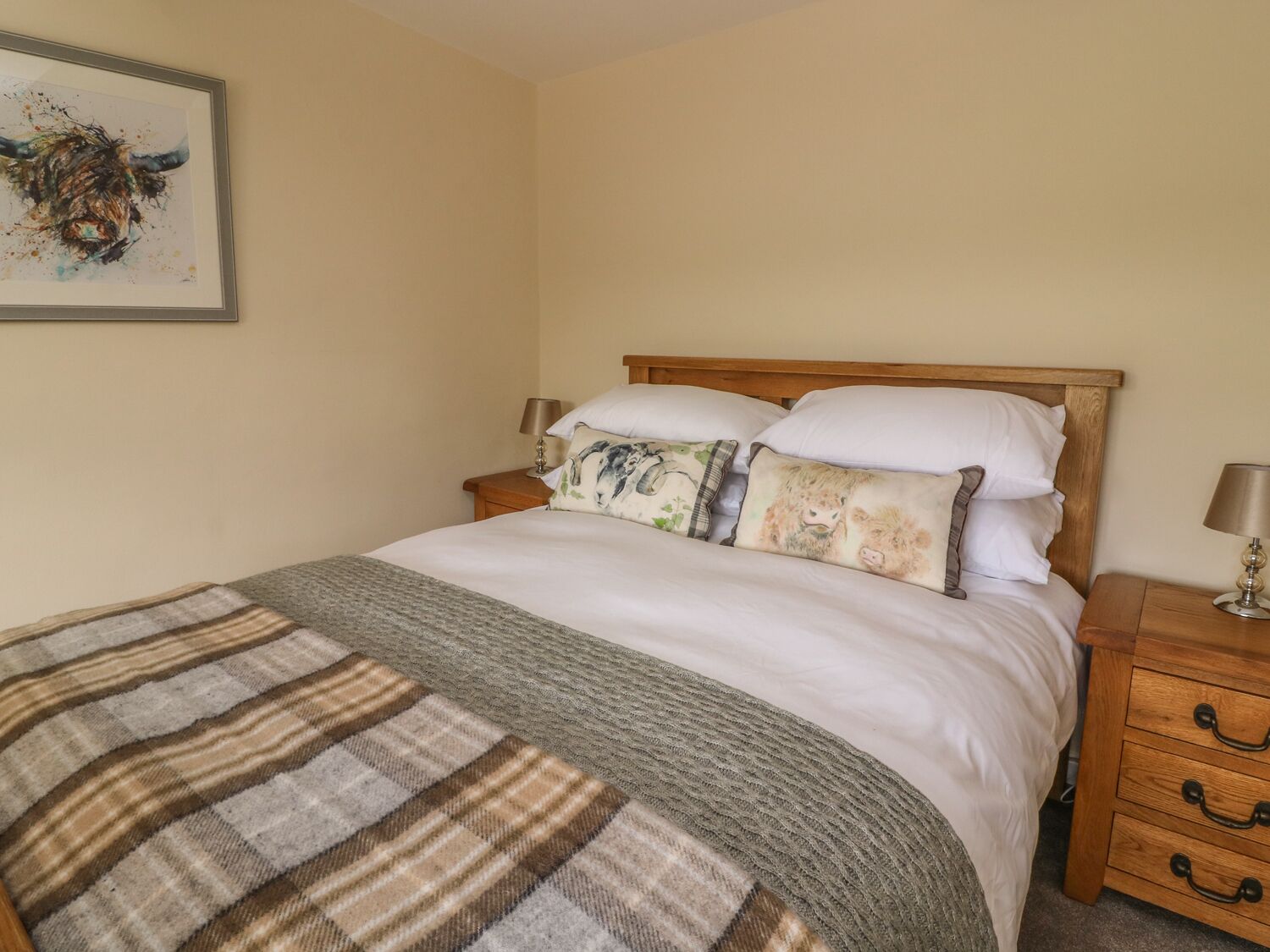 A neatly made bed with a striped blanket, a wooden headboard, and two bedside tables with lamps.