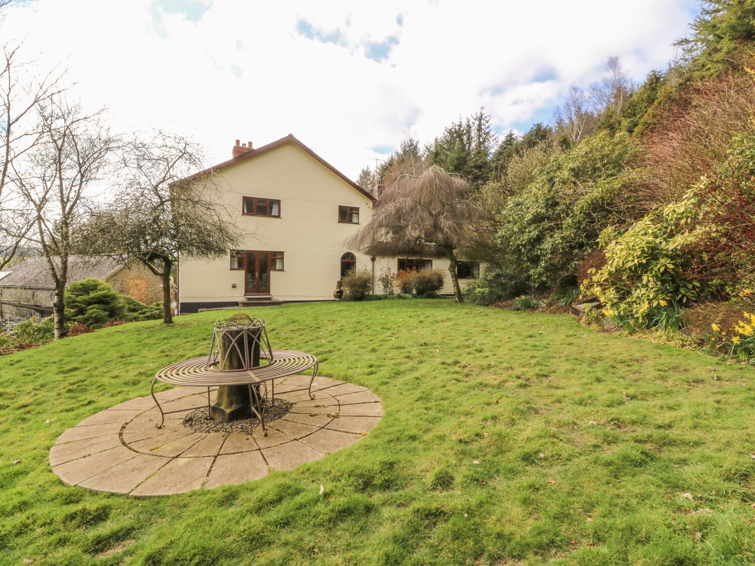 A two-story house with a circular patio in the front yard.