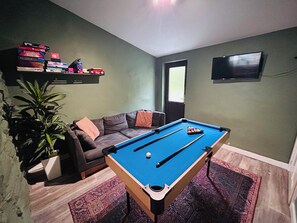 A room with a pool table, a sofa, a television, and a plant. - Stiniog Lodge (Blaenau Ffestiniog)