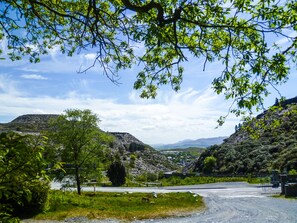 A rural road with a bridge in the distance, surrounded by lush greenery and hills. - Stiniog Lodge (Blaenau Ffestiniog)