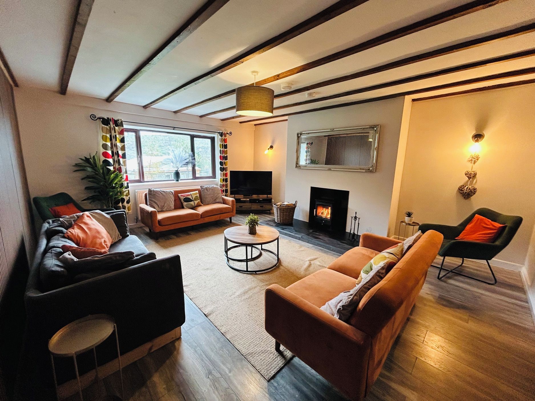 Ein modernes Wohnzimmer mit Kamin, Sofas, einem Fernseher und einem großen Fenster.