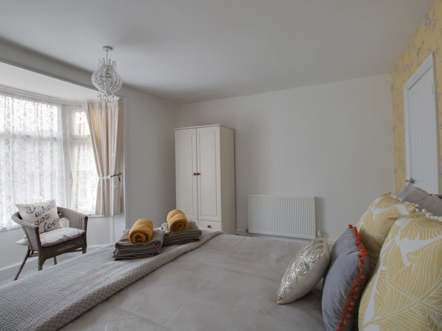 A bedroom with a bed, a chair, a wardrobe, and a radiator.