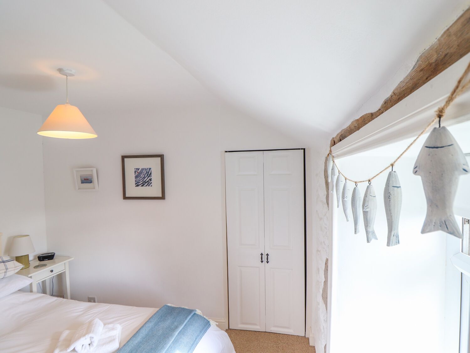 Ein Schlafzimmer mit einem Bett, einem Nachttisch, einer Lampe, einem Kleiderschrank und einer Wand mit gerahmten Bildern.