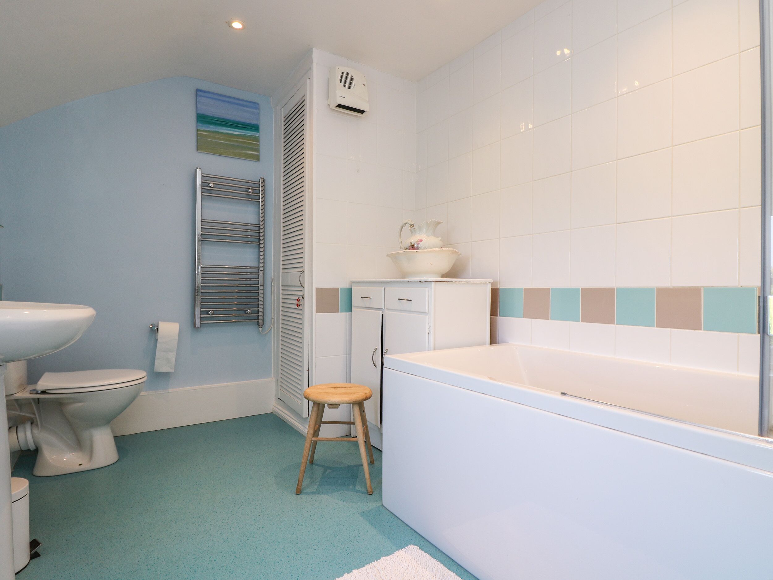 A bathroom with a toilet, sink, bathtub, and a towel rack.