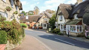 A street lined with traditional buildings, including a pub with outdoor seating and a sign for 'The Bell Inn'. - White Haven (Sandown)