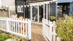 A residential property with a covered patio, a white picket fence, and a small garden area. - White Haven (Sandown)