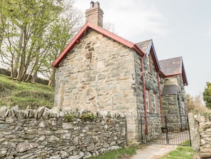 A stone building with a red roof and a stone wall in front.
