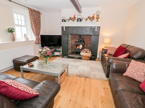 A cozy living room with a fireplace, leather sofas, a coffee table, and a television.