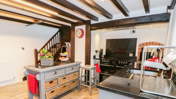 A modern kitchen with a built-in oven, a stainless steel sink, and a red oven mitt hanging on the wall. - Hafodty (Conwy)