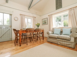 Cozy living room with a dining table for four, plaid sofa, and large window.