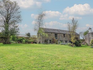 A stone building with a large lawn in front. - Erin Cottage (Looe)