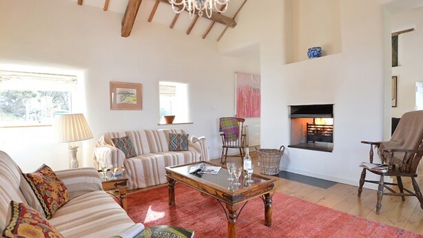 A spacious living room with a fireplace, striped sofa, and a red carpet. - Cefn Isaf (Porthmadog)