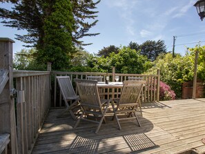 A wooden deck with a table and chairs, surrounded by a wooden fence and lush greenery. - Waterson (Weymouth)