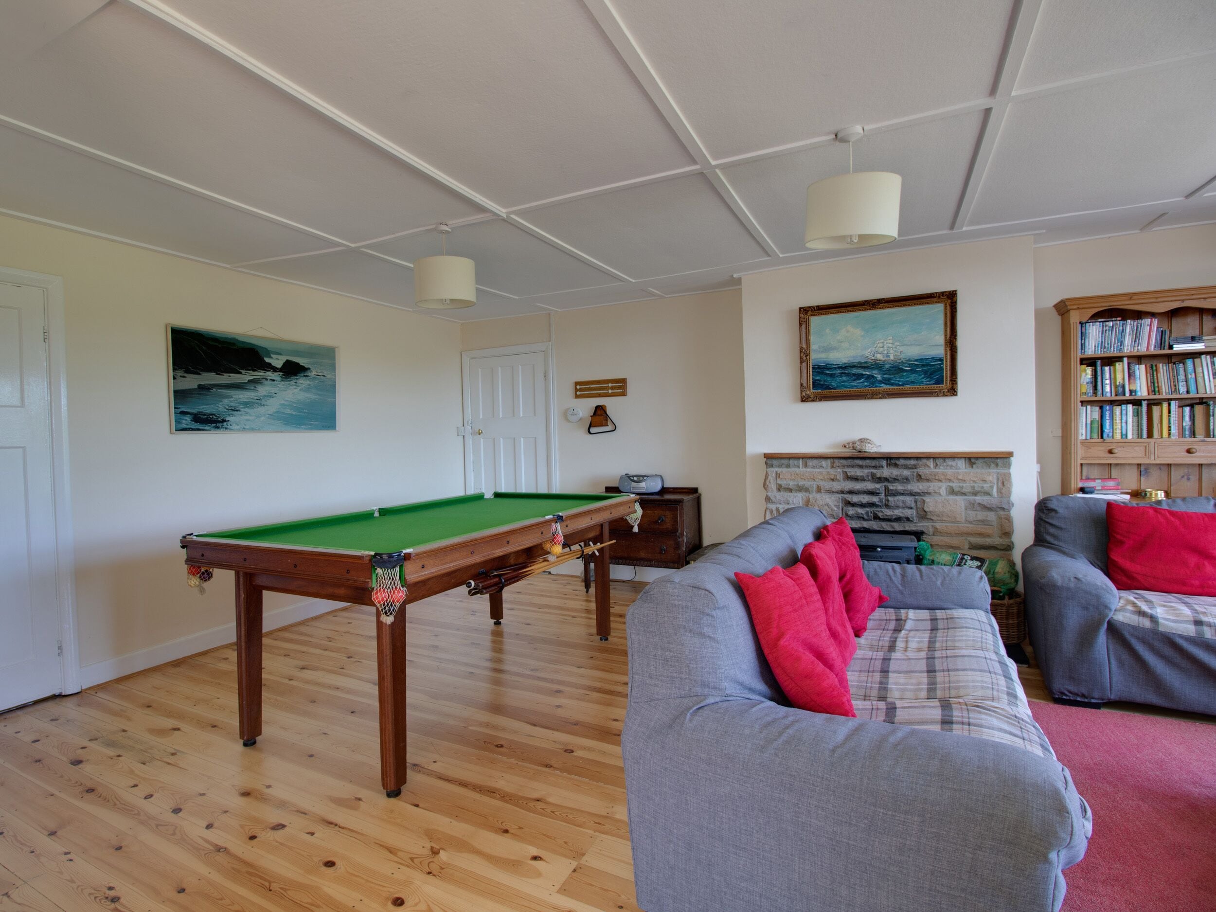A living room with a pool table, a fireplace, a bookshelf, and a sofa.