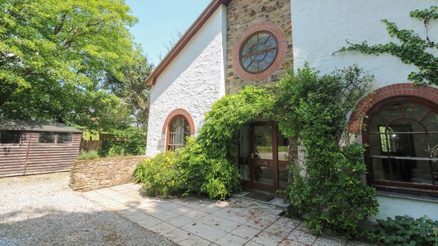 A building with a stone facade, arched windows, and a door with a glass panel. - Beggars Roost (Truro)
