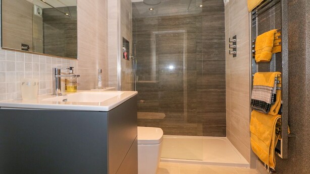 A modern bathroom with a glass-enclosed shower, a white sink, and a toilet.