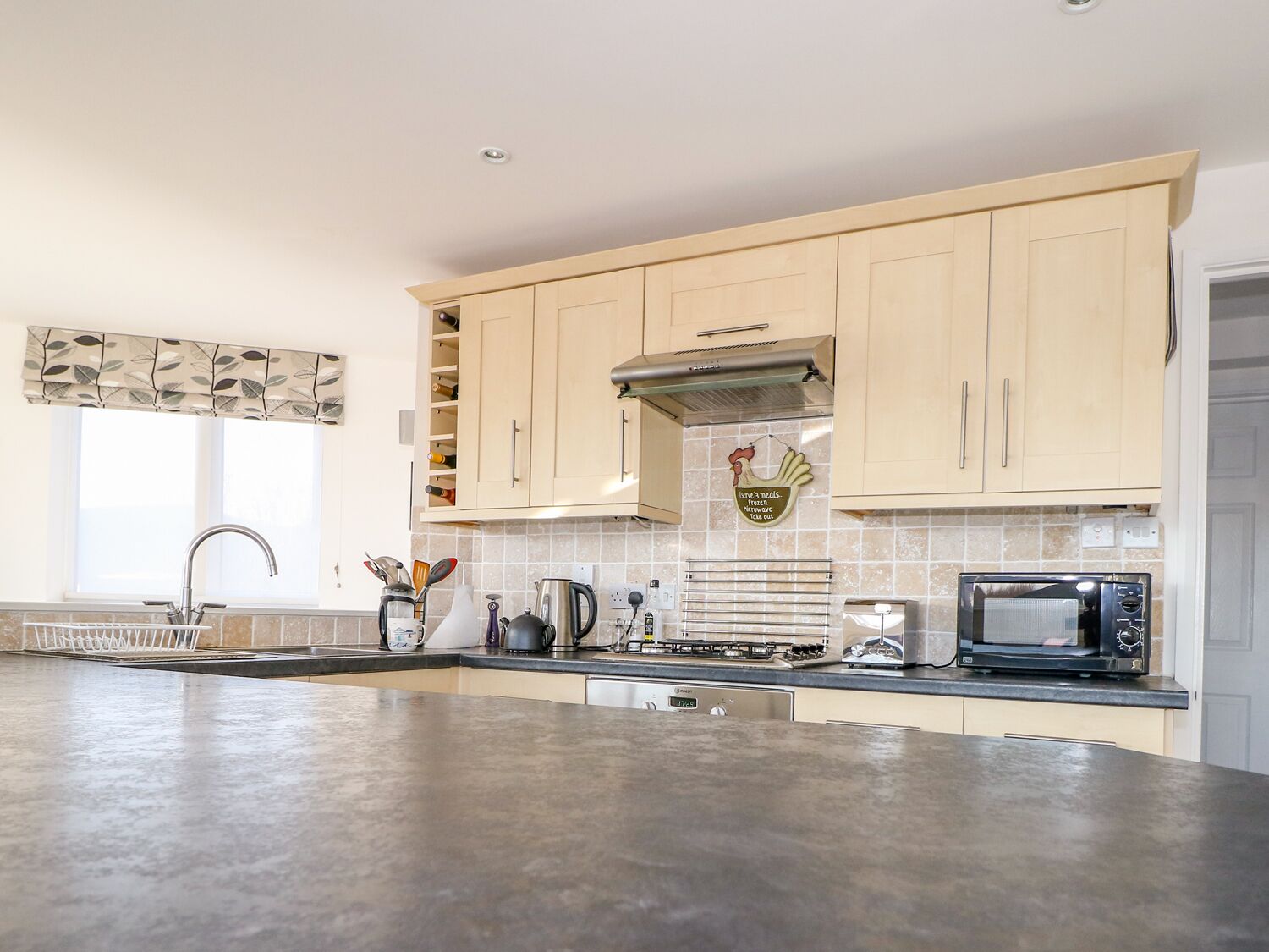 Una cocina moderna con armarios de madera clara, un lavamanos de acero inoxidable y una isla grande.