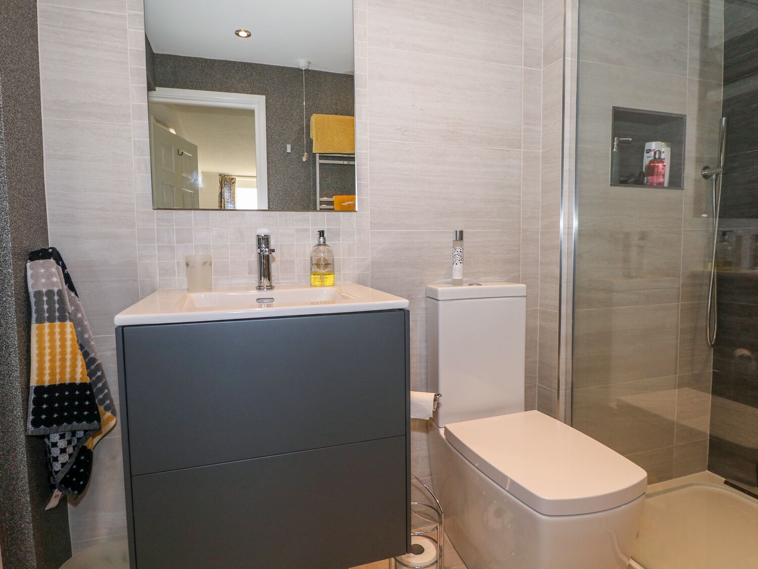 Un baño moderno con un espejo grande, un lavabo, un inodoro y una zona de ducha.