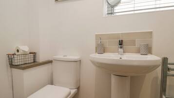 Un baño con inodoro, lavamanos y ventana con persianas.