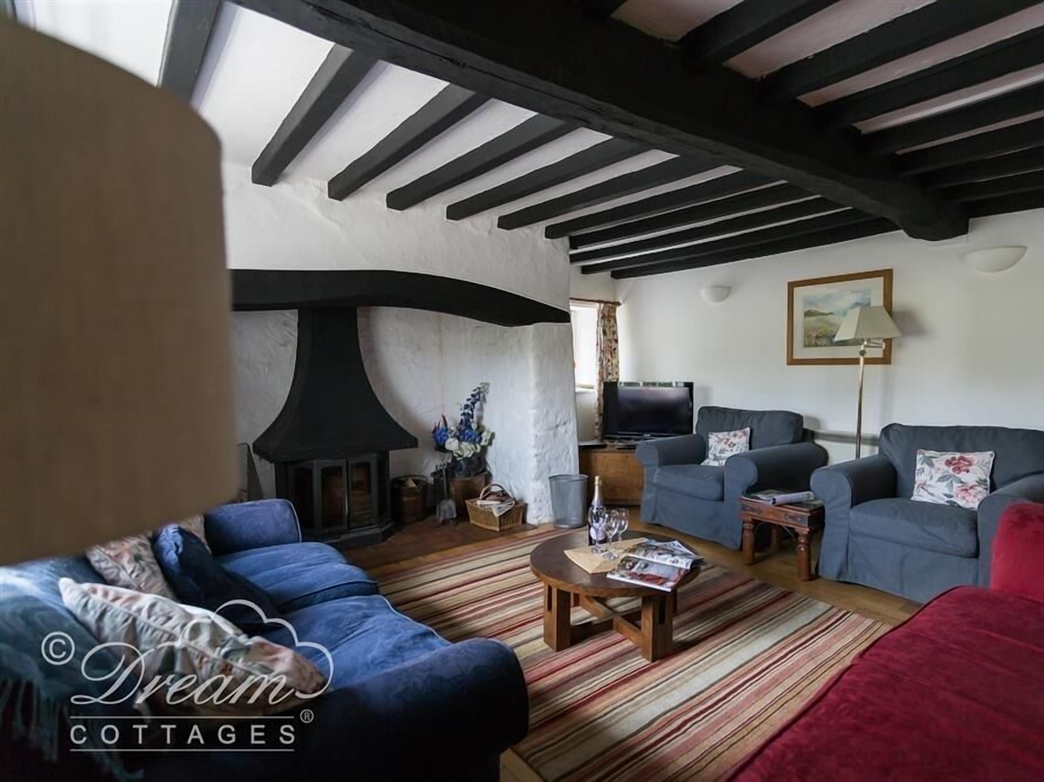 A cozy living room with a fireplace, two sofas, a coffee table, and a television.