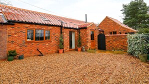 A brick house with a tiled roof, a gravel driveway, and potted plants. - Honey Buzzard Barn (Fakenham)