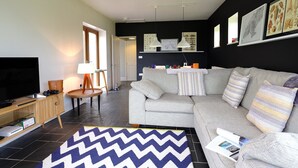 Un salon moderne avec un canapé gris, un téléviseur, une lampe et un tapis.
