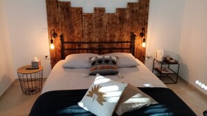 A bedroom with a wooden headboard, two bedside tables, a bed with pillows and a blanket, and wall-mounted reading lights. - La Gurlanne (Lasseran)