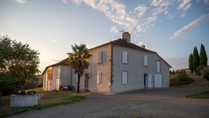 A large, two-story house with a paved driveway and a palm tree in the foreground. - La Gurlanne (Lasseran)