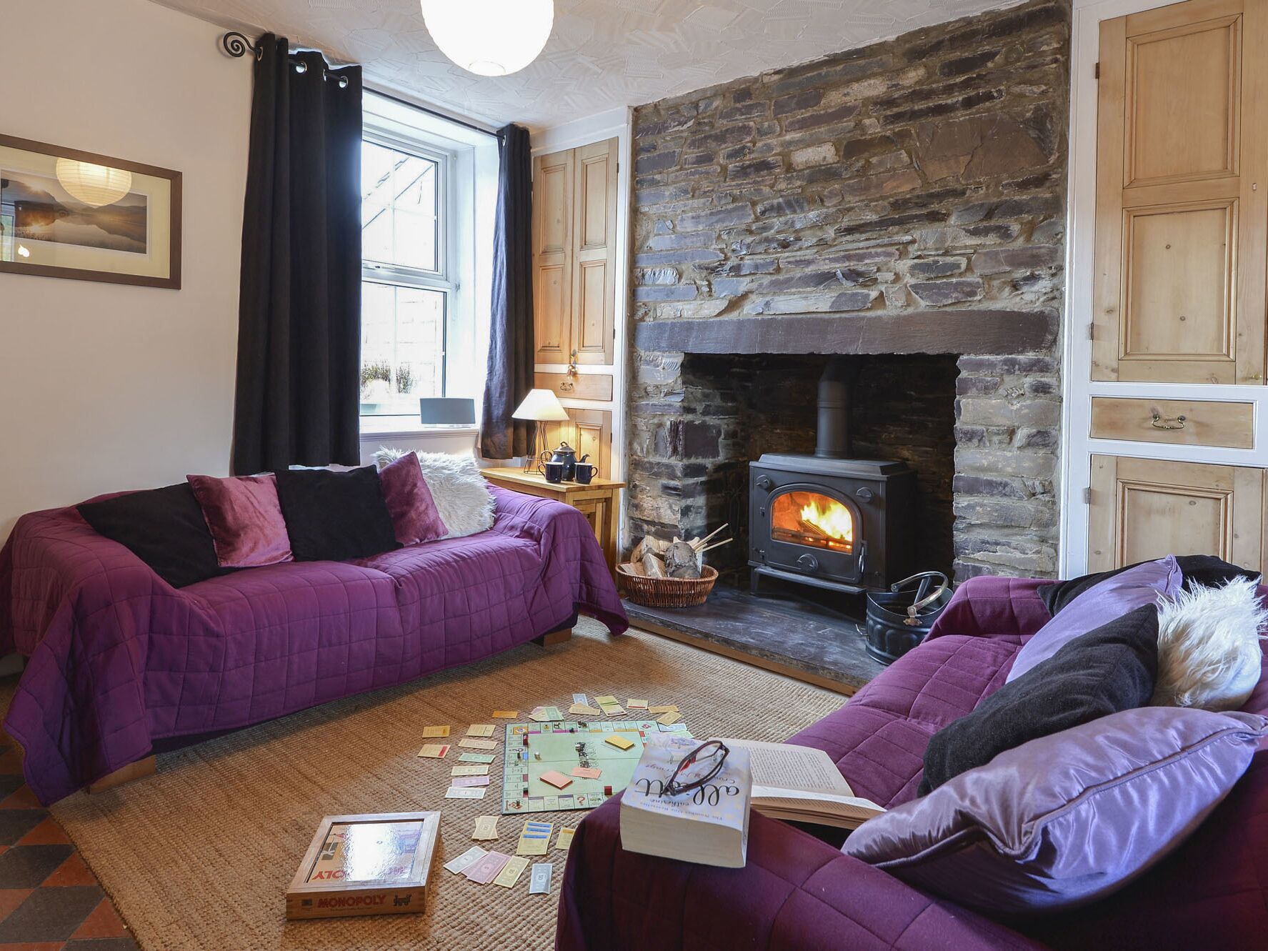 Ein gemütliches Wohnzimmer mit Kamin aus Stein, einer Couch und einem Gesellschaftsspiel.