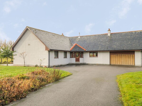 A single-story house with a sloped roof, a front porch, and a garage. - The Glebe (Invergordon)