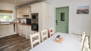 A kitchen with white cabinets, a microwave, an oven, and a dining table with chairs.