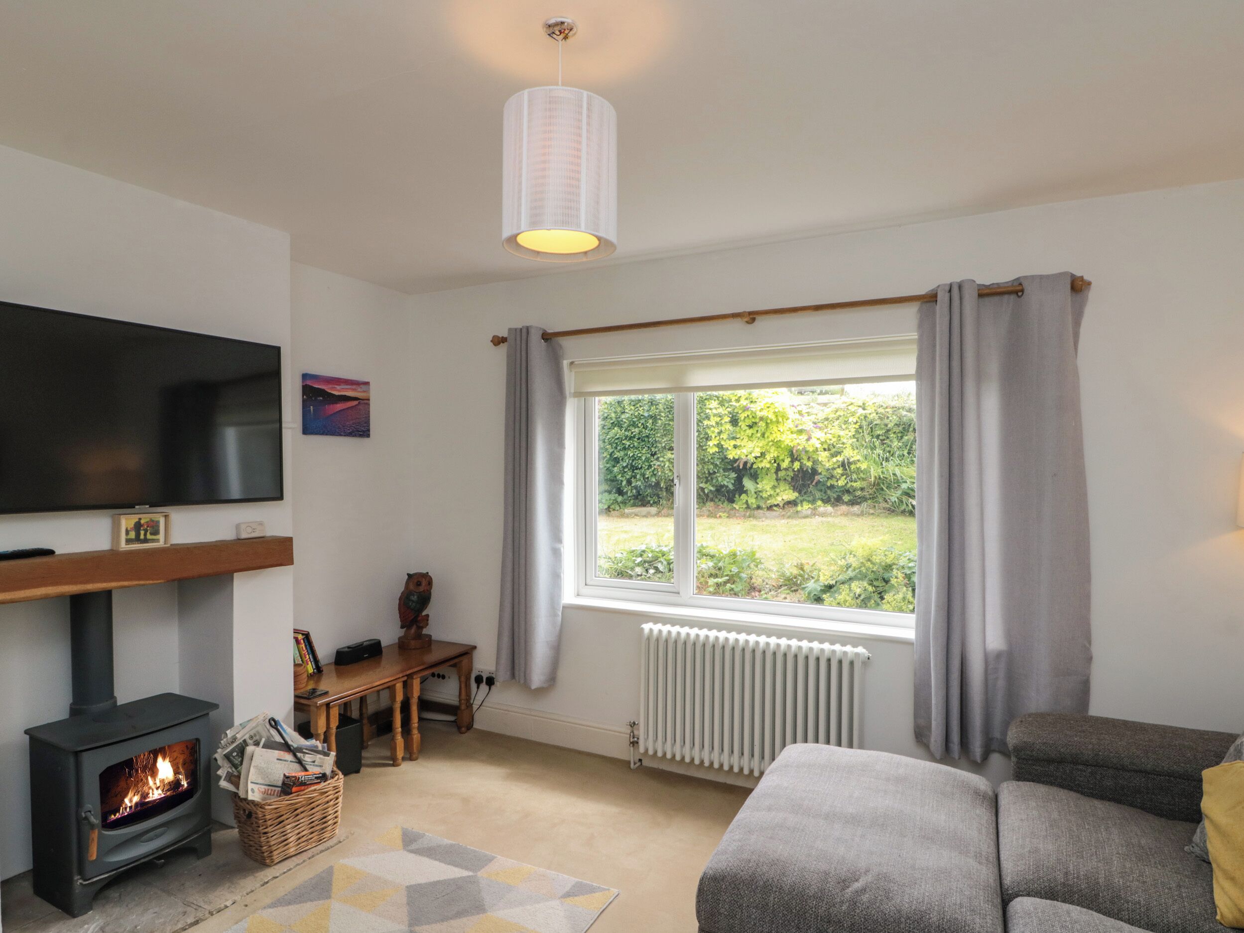 A living room with a fireplace, a television, a sofa, and a window with curtains.