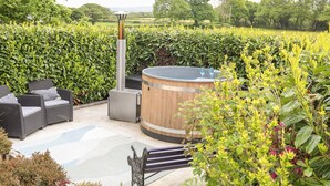 A patio area with a hot tub, wicker furniture, and a wooden barrel.