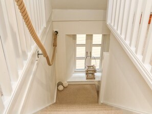Stairwell leading to a landing with a window and a wooden ladder.