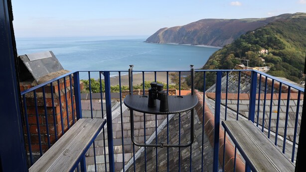 A balcony with a view of the sea and hills.