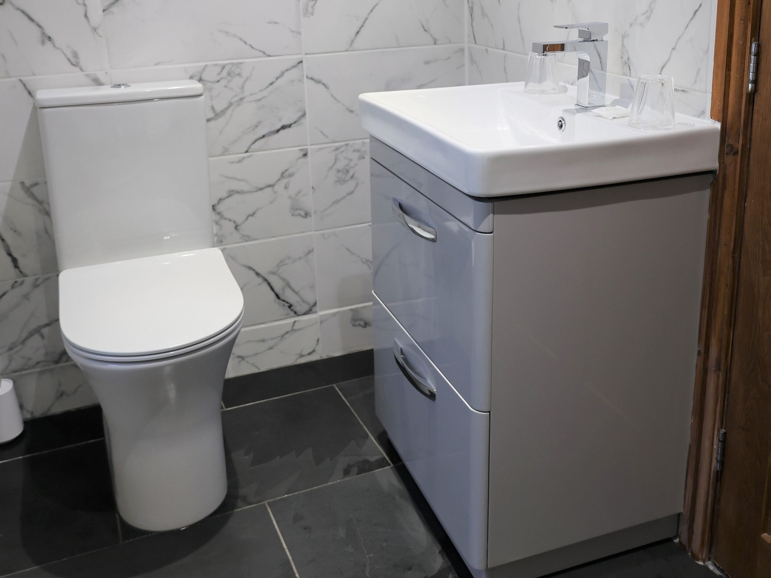 A bathroom with a toilet, a sink, and a cabinet.