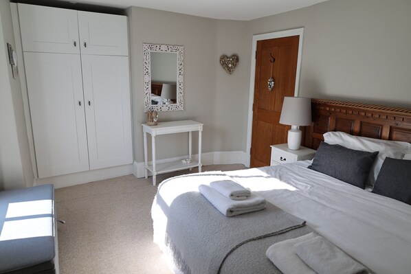 A bedroom with a bed, a nightstand, a dresser, a mirror, and a door. - The Penthouse Lynmouth Bay (Lynton)