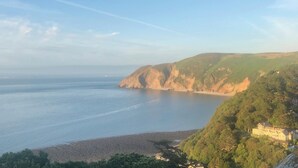 A coastal landscape with a large building on a hillside overlooking the sea.