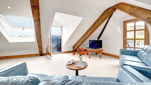 A spacious loft with a sloped ceiling, a large TV, and a cozy seating area with a coffee table.
