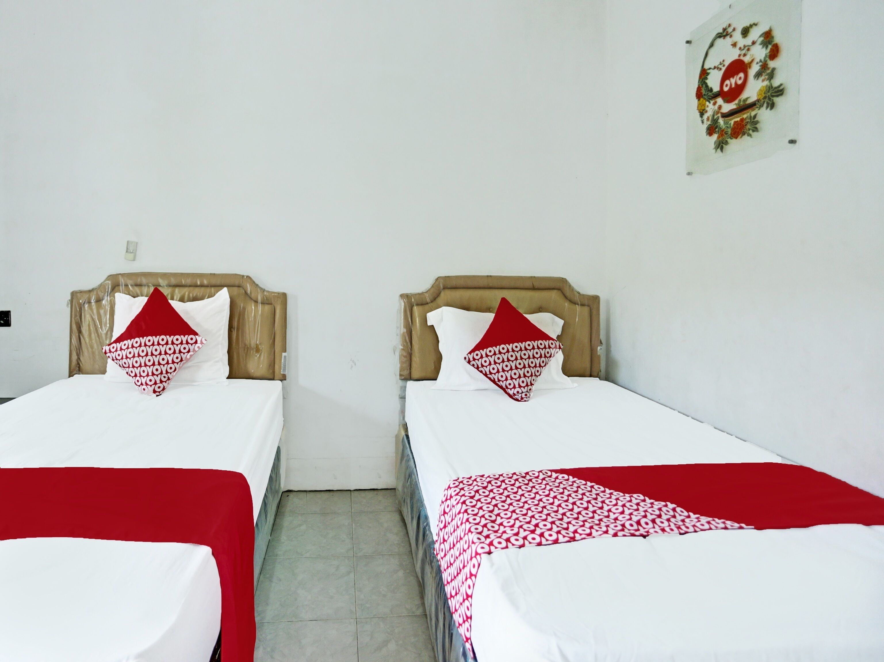 Two single beds with wooden headboards, white bedding, and red pillows with a repeated pattern.