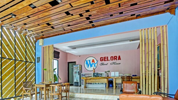 Un área de recepción con techo de madera, una mesa de recepción y un letrero que dice "GELORA Guest House".