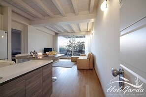 A modern kitchen with a wooden island, a dining area with a sofa, and a view of the outdoors.