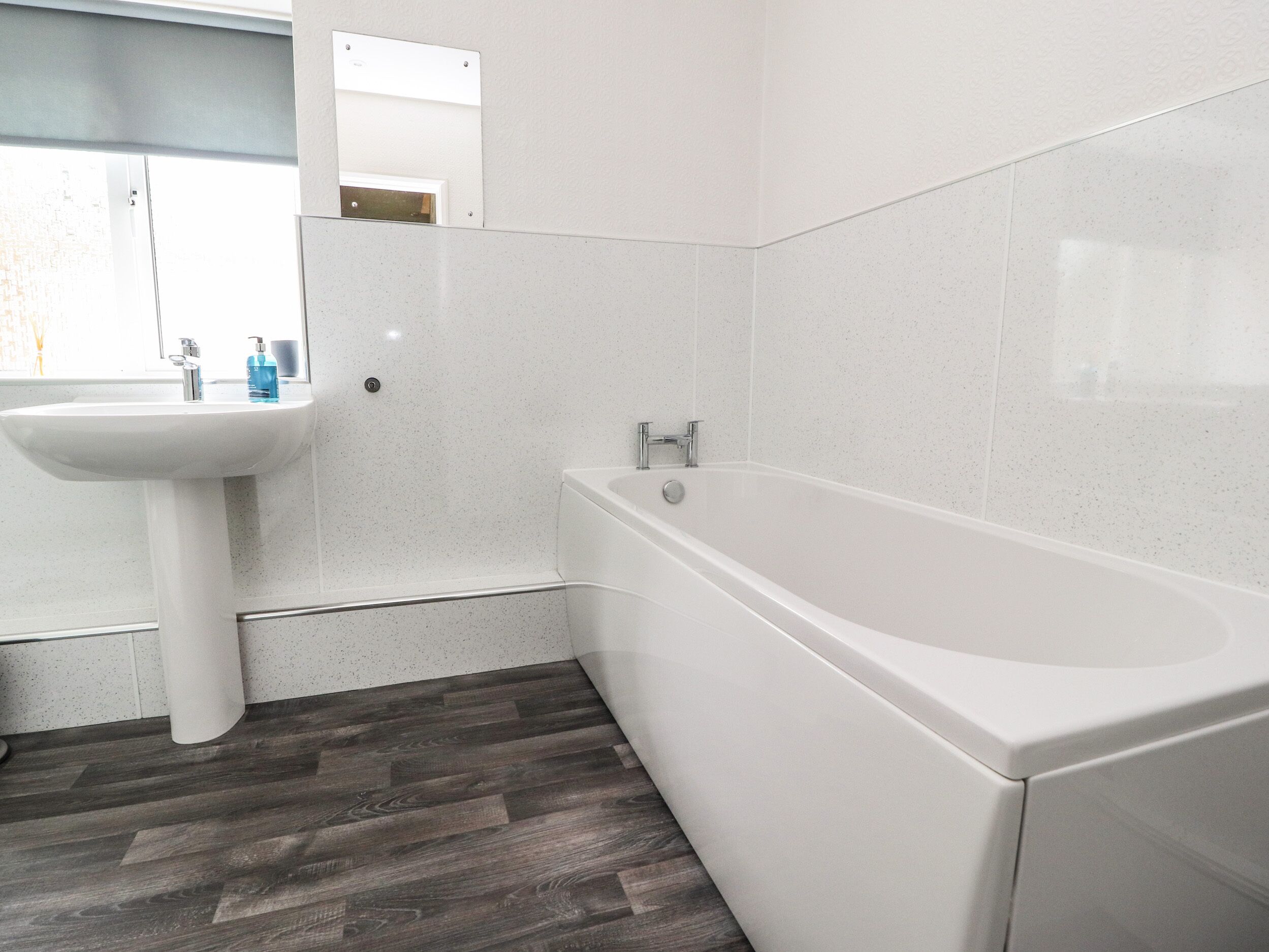 Ein Badezimmer mit einem weißen Waschbecken, einer Badewanne und einem Spiegel.