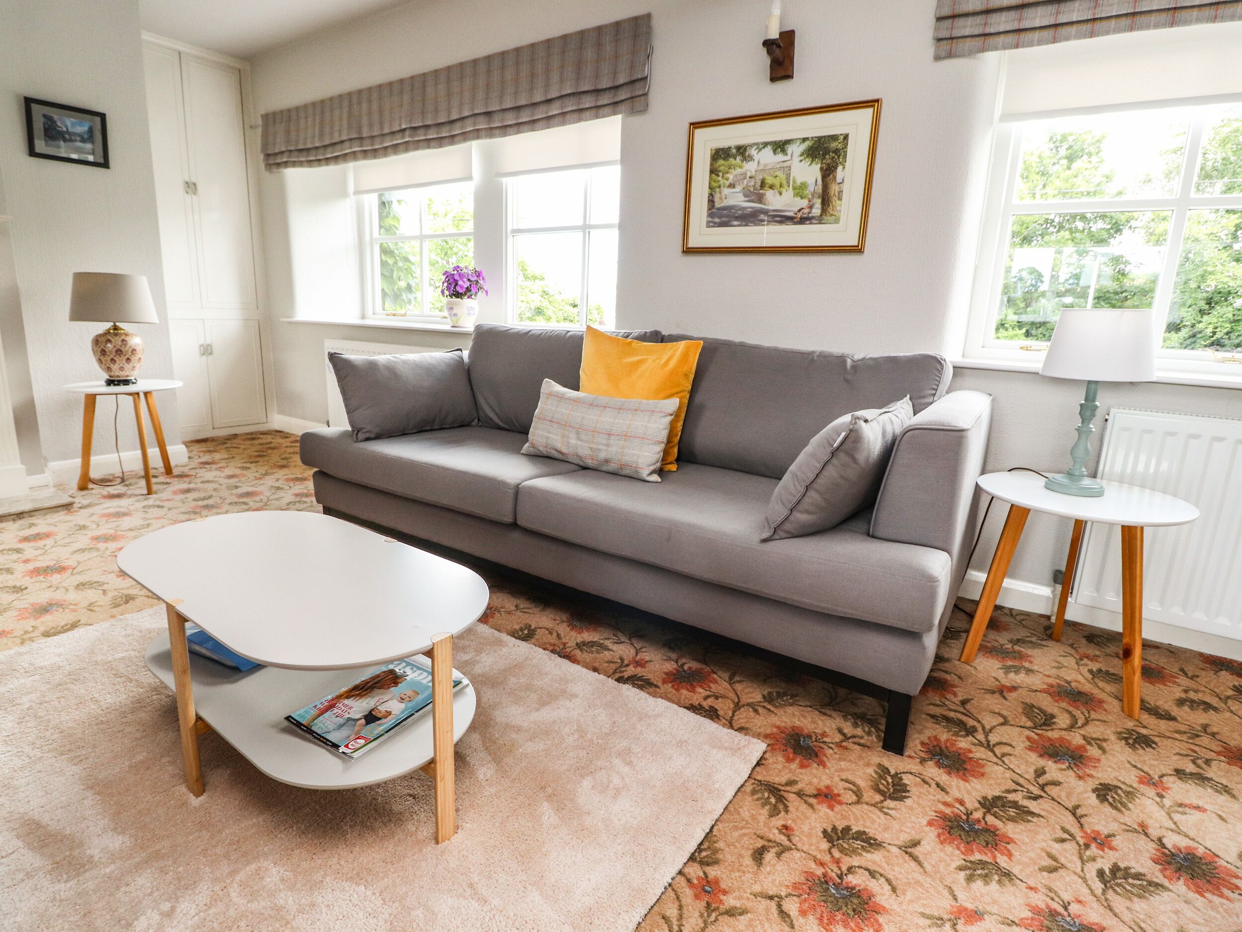 A living room with a grey sofa, a white coffee table, and a floral carpet.
