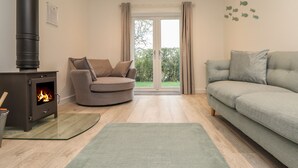 Una sala de estar con estufa de leña, un sofá gris y un tapete verde.