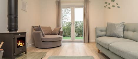 A living room with a wood-burning stove, a grey sofa, and a green rug.