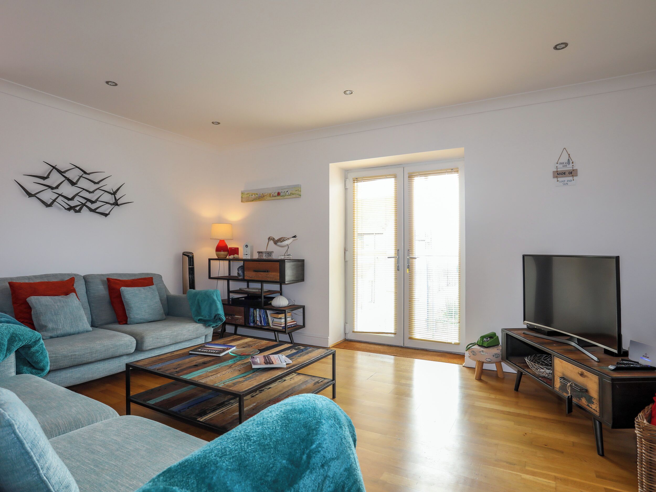 A modern living room with a sofa, coffee table, TV, and a bookshelf.