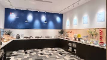 A modern kitchen with a geometric patterned floor, a blue accent wall, and various kitchen appliances and utensils.