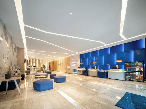 A modern hotel lobby with a reception desk, seating areas, and a clear view of the reception counter. - Holiday Inn Express Jiangmen Jianghai by IHG (Jiangmen)