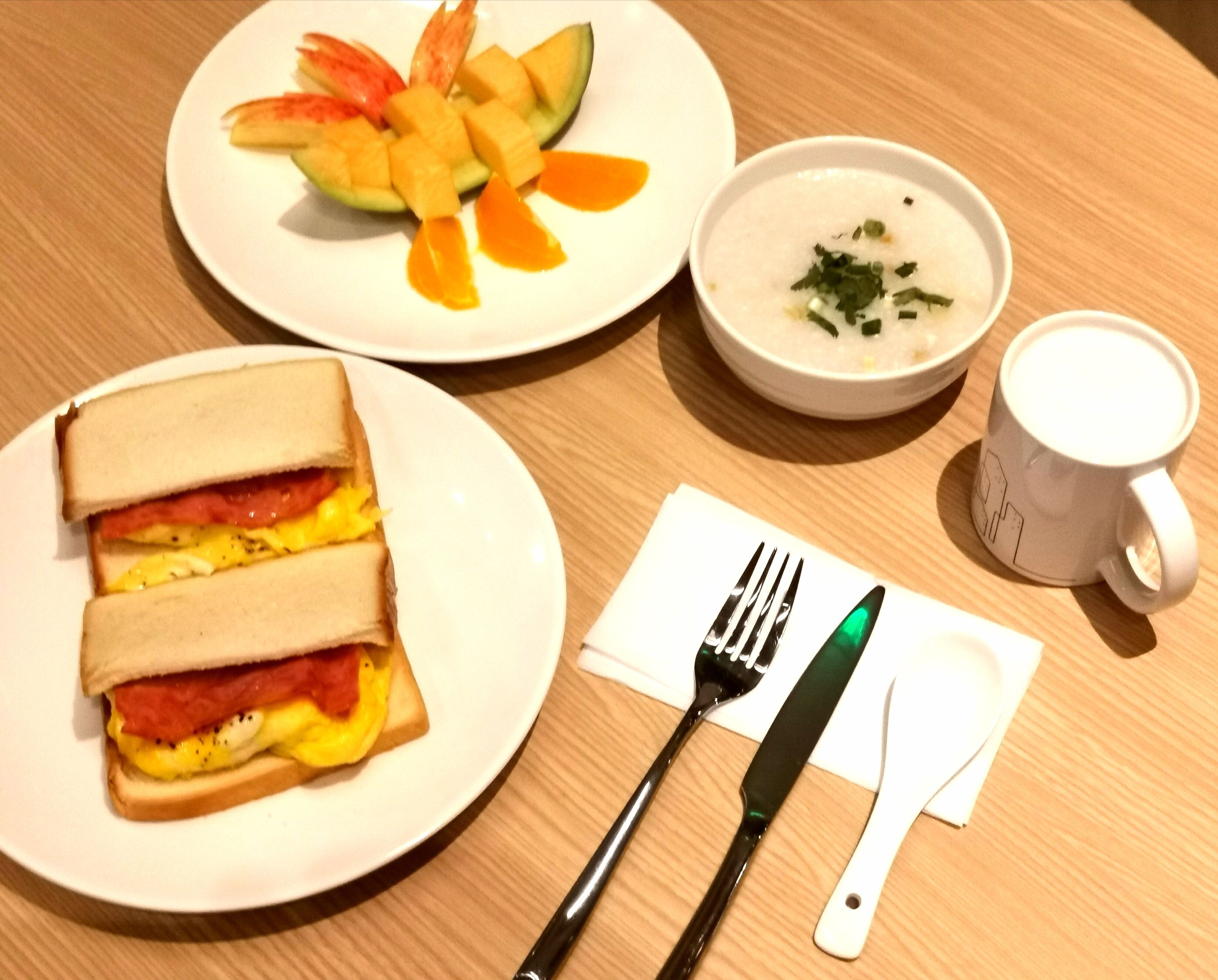 A meal consisting of a sandwich, soup, and a cup of coffee on a wooden table.